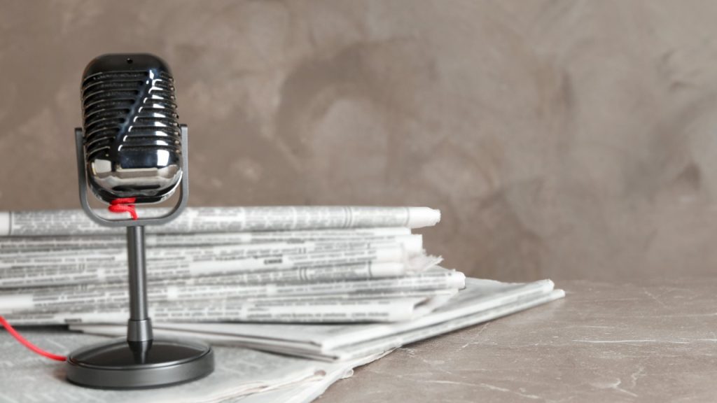 A microphone and stand on a pile of newspapers.