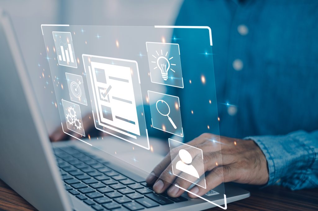 Man sat at laptop with his hands resting next to the keyboard. A graphic with icons (graphs, a light bulb, a magnifying glass and human outline) is superimposed over the laptop.